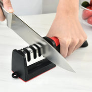 Person sharpening a knife on a black and red sharpener with a white background.