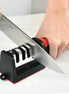 Person sharpening a knife on a black and red sharpener with a white background.