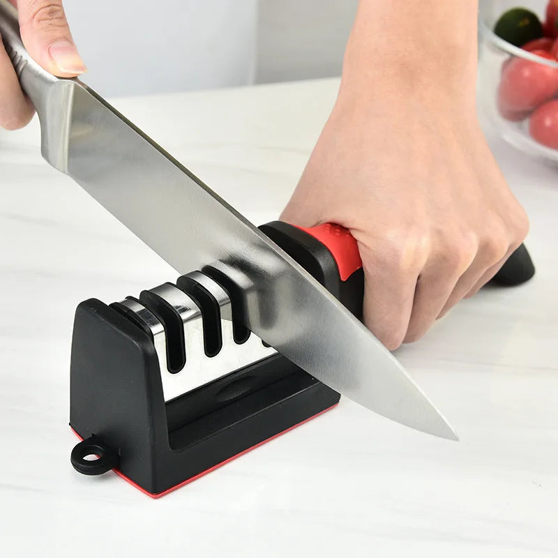 Person sharpening a knife on a black and red sharpener with a white background.