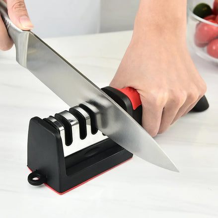 Person sharpening a knife on a black and red sharpener with a white background.