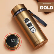 Gold thermos bottle with digital temperature display on a beige background