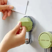 Hand using a green suction hook to attach a piece of paper to a white surface.