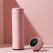 Pink thermos bottle and digital clock on a pink background