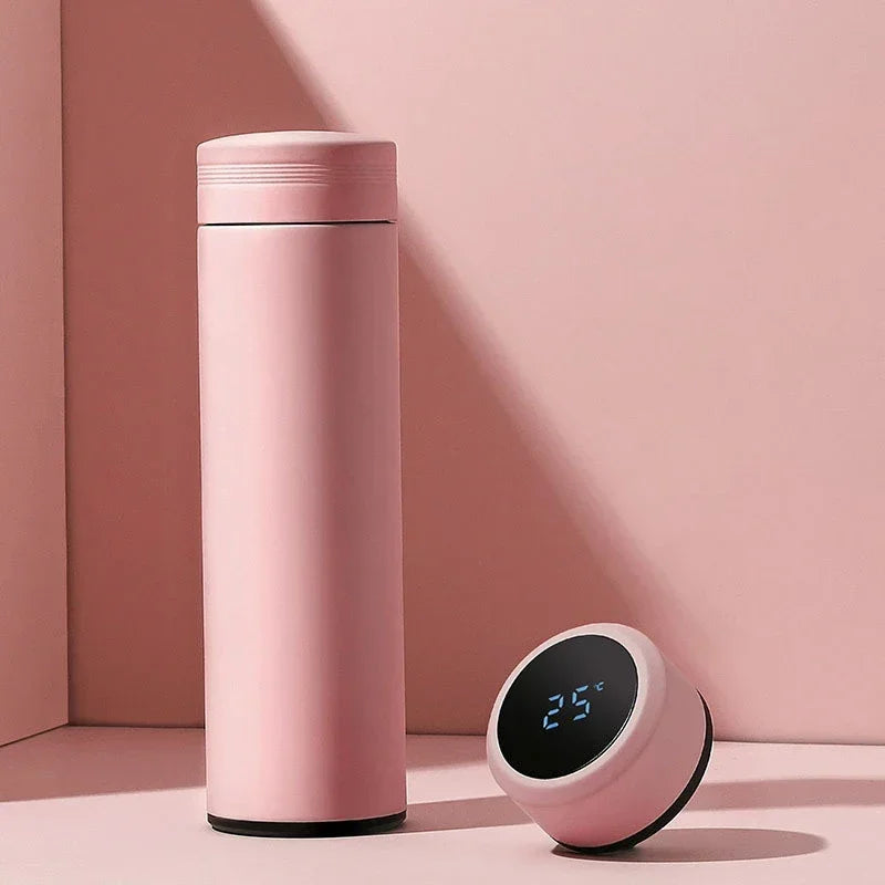 Pink thermos bottle and digital clock on a pink background
