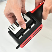 Person using a black and red knife sharpener on a white background