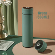 Green thermos bottle with digital temperature display on a table with decorative items.