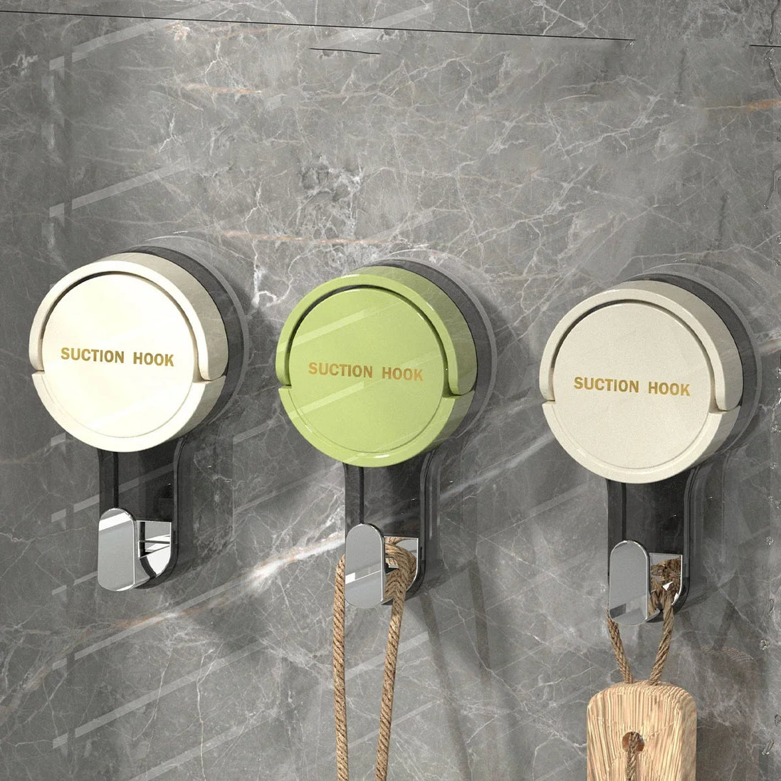 Three suction hooks on a marble wall with ropes hanging from them.
