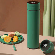 Green thermos bottle with digital display on a table with fruits and cookies